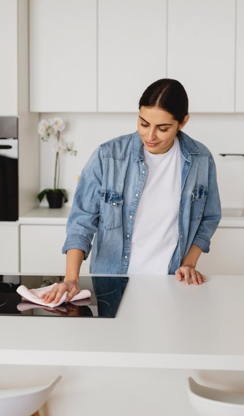 homeowner wipes stove clean after learning the Cleaning Schedule checklist at chelsearclarke.co