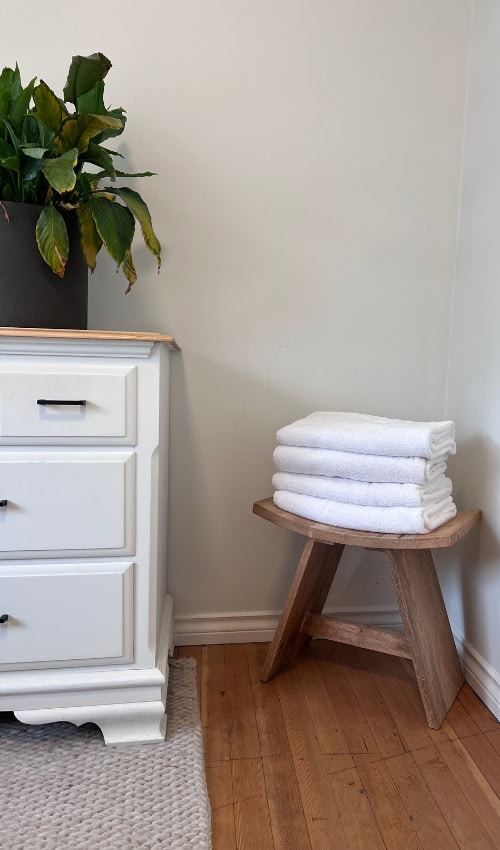 a stack of towels on a stool next to a plant